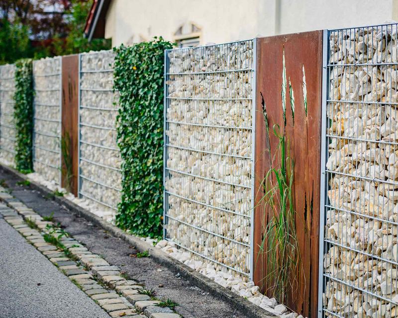 abwechselnde Sichtschutzelemente aus Metall, Stein und natürlichen Hecken