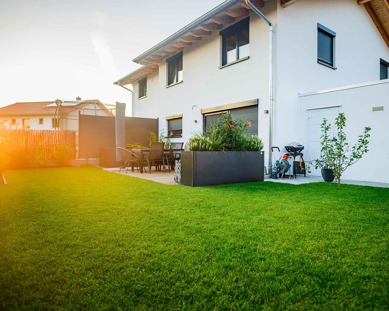 Aufnahme eines Einfamilienhauses mit großer Rasenfläche und Terrasse
