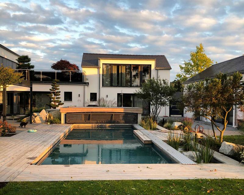 abendliche Aufnahme eines modernen Einfamilienhauses mit großem Biopool und Holzterrasse