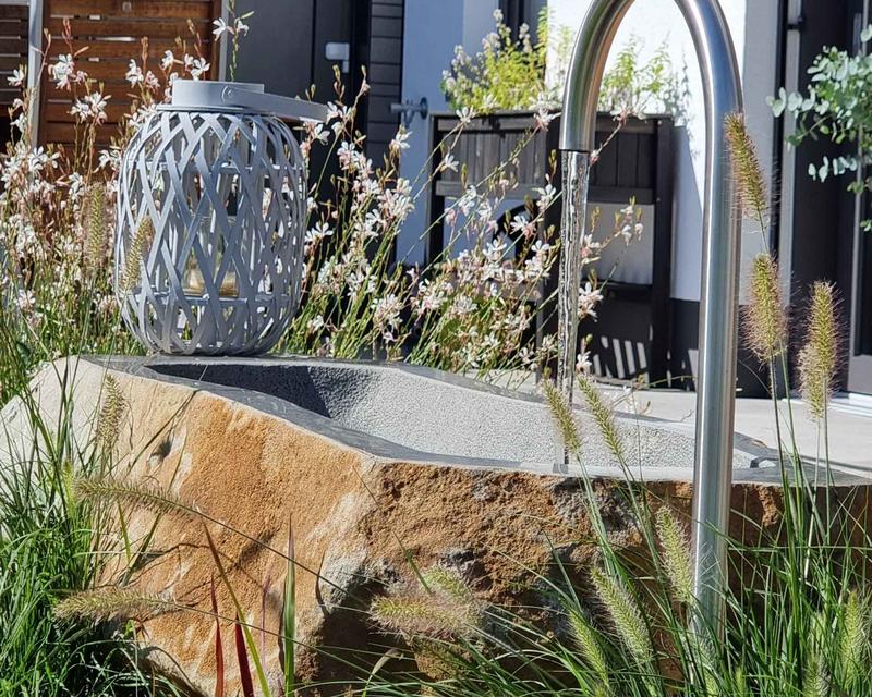moderner Brunnen in Blumenbeet mit Steintrog