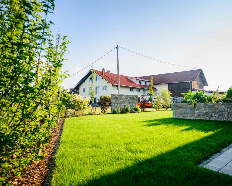 sommerliche Aufnahme von großer Rasenfläche vor einem Einfamilienhaus