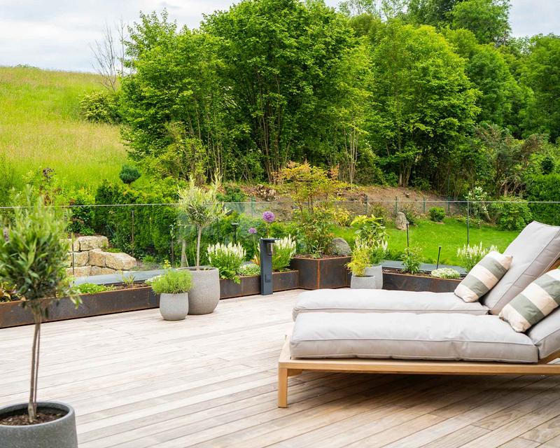 moderne Holzterrasse mit Liegestühlen und Beeten