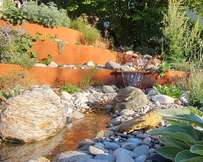Bachlauf durch einen Hanggarten mit rostigen Metallabstufungen