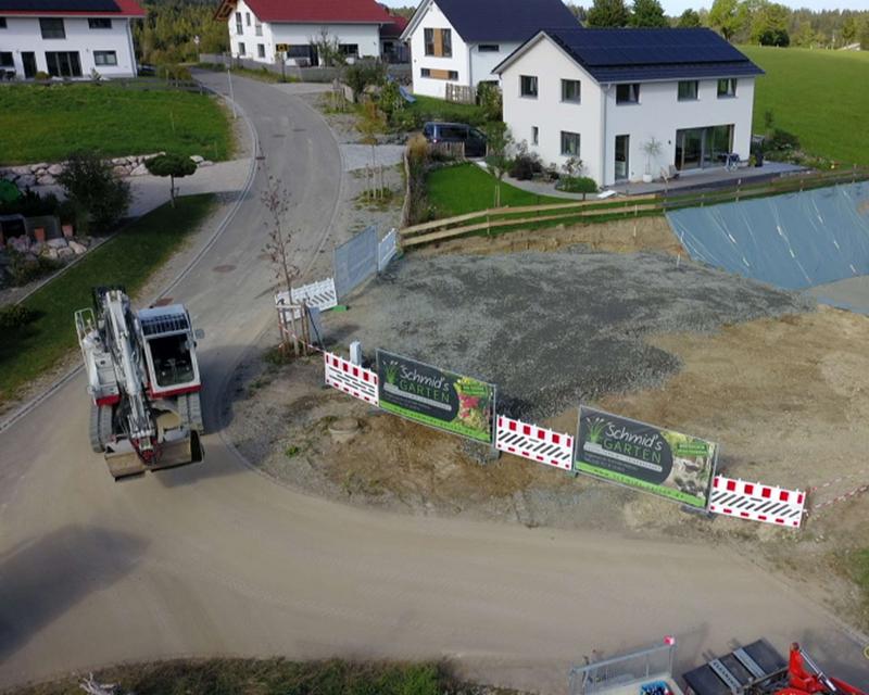Drohnenaufnahme eines Baggers neben einer großen Aushub Grube