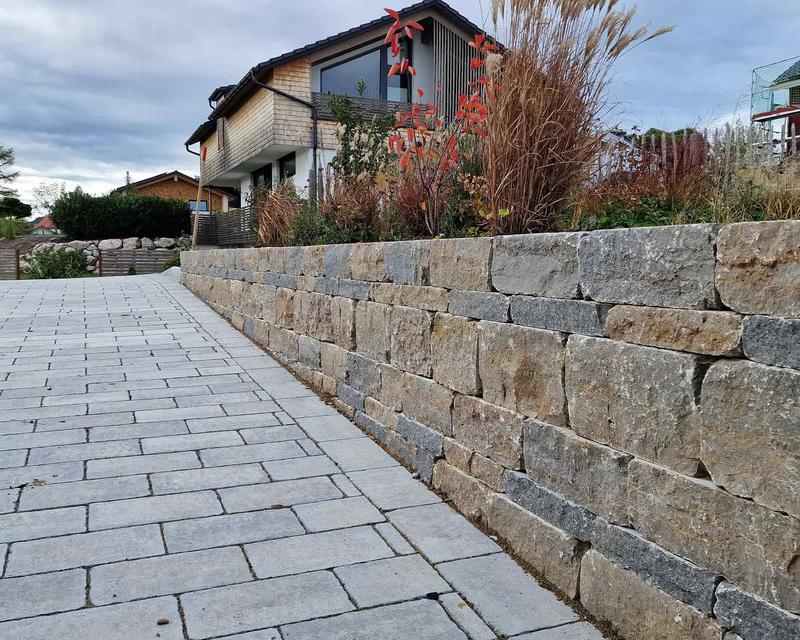 gepflasterte Hofeinfahrt mit einer Natursteinmauer Begrenzung