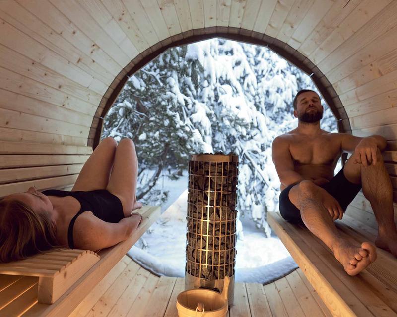 Fass Sauna mit zwei Personen im winterlichen Garten