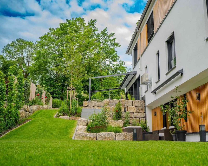 Aufnahme eines Hanggartens an einem Wohnhaus mit Sichtschutz, Treppen und Steinen 