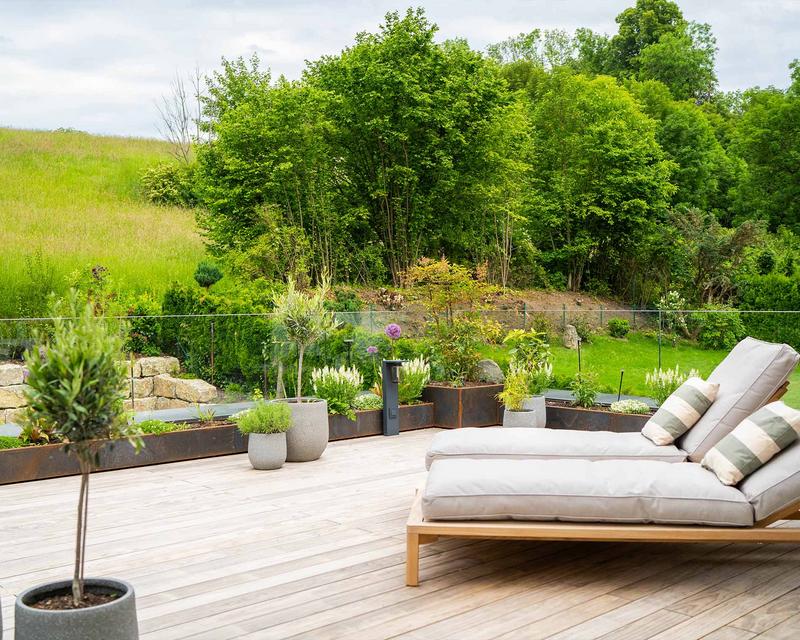 Aufnahme einer Holzterrasse mit Leigestühlen und Beeten ringsum