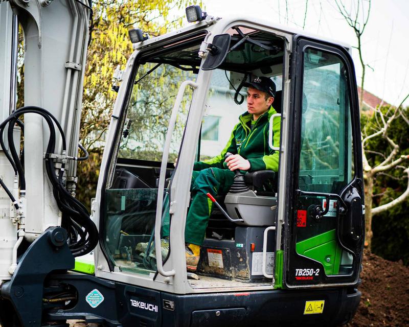 ein Mitarbeiter von Schmids Garten in einem Bagger