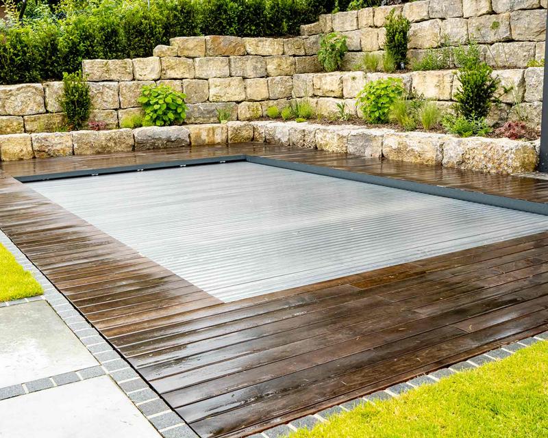 Aufnahme eines abgedeckten Pools in einem Hanggarten mit schöner Holzterrasse 