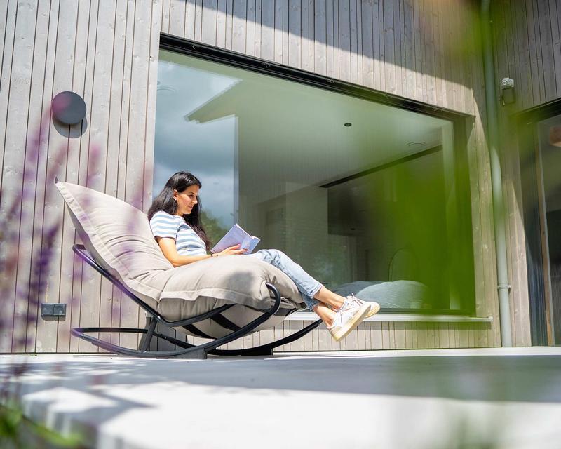 Frau sitzt auf Sonnenliege auf der Terrasse