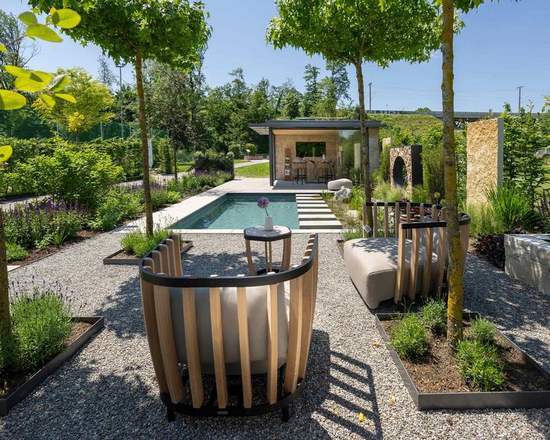 Blick über den Schaugarten von Schmids Garten mit Naturpool, schattigen sitzgelegenheiten und bunter Bepflanzung