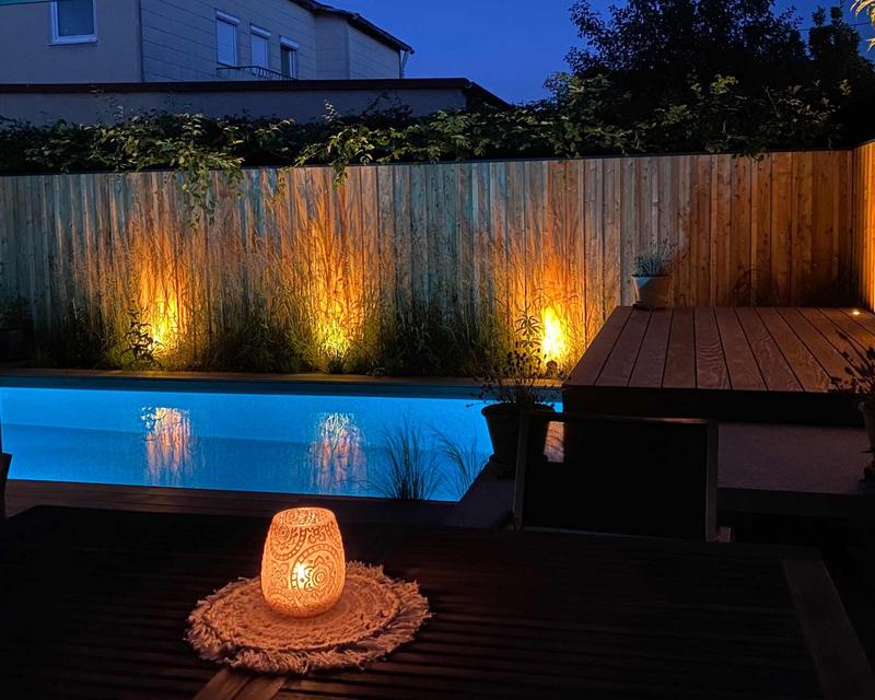 Nachtaufnahme eines Pools mit beleuchteten Sichtschutzelementen und Unterwasser Beleuchtung