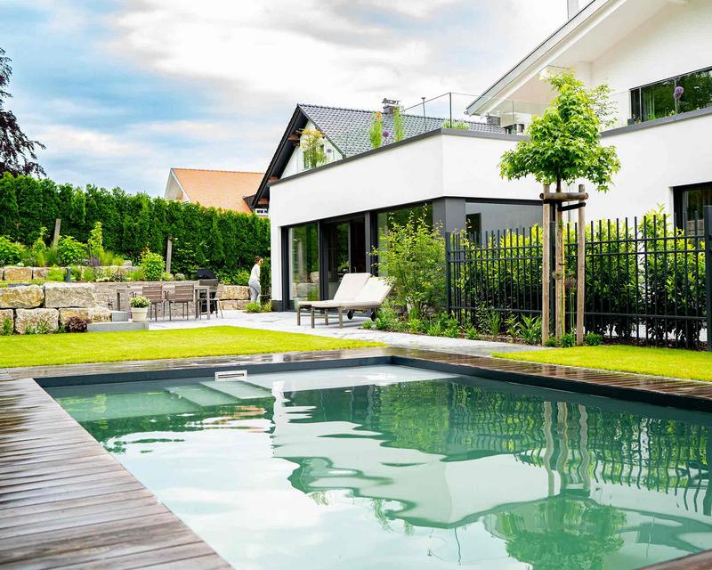 Wasseroberfläche eines Biopools und dem Garten herum vor einem Wohnhaus
